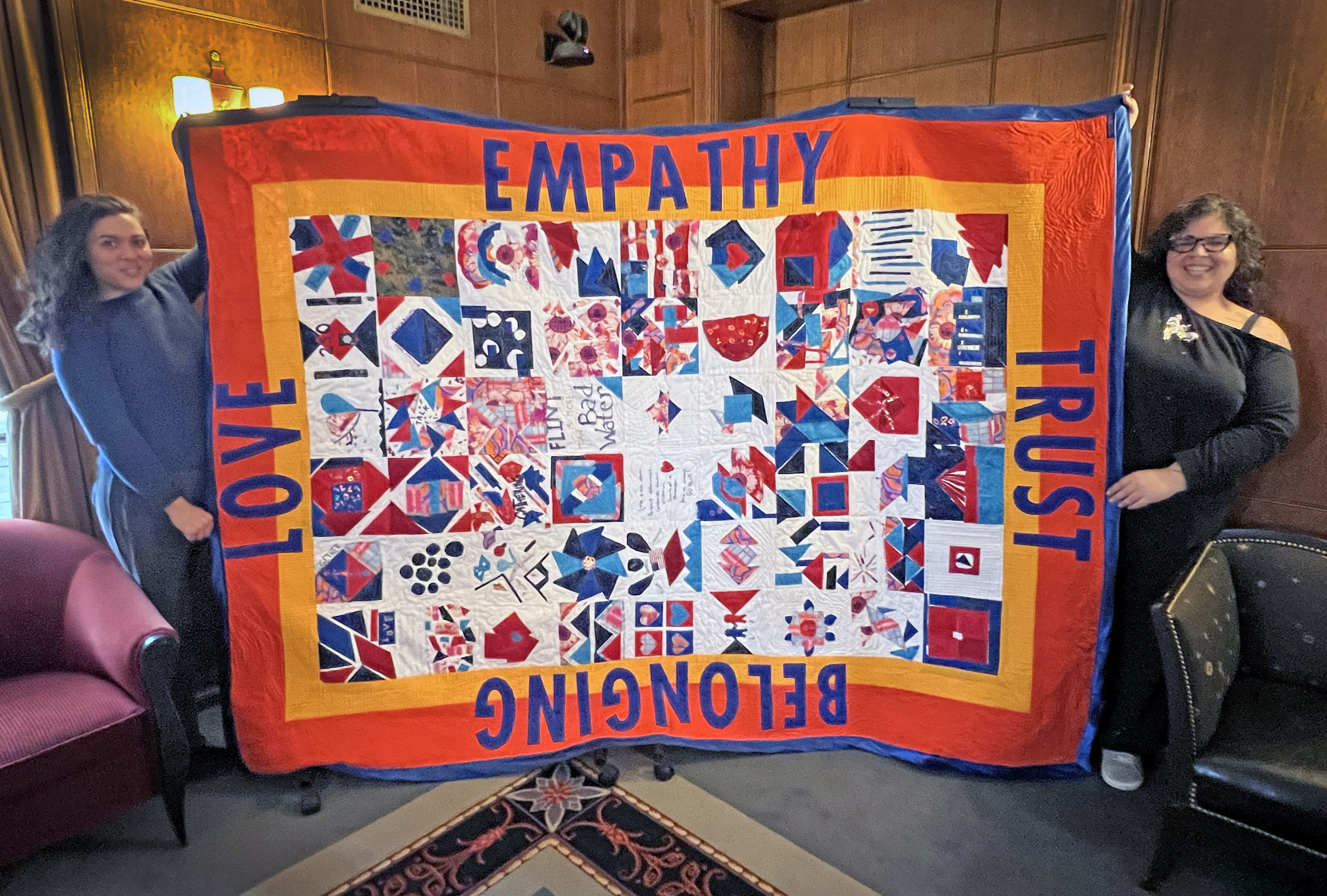 Artists hold up the finished quilt